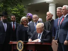 U.S. President Donald Trump flanked by religious leaders as he signs an executive order on religious freedom May 4, 2017. 