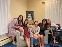 Lisieux House ladies holding up a picture of St. Therese of Lisieux from a feast day celebration they had in her honor.