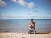 Man kneeling at beach / 