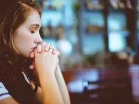 A young woman prays in a church.