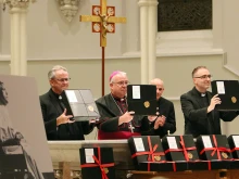 Father Thomas Dailey, O.S.F.S.; Philadelphia Archbishop Nelson J. Perez; Msgr. Gerald Mesure, archdiocesan chancellor; and Father Sean Bransfield, vice chancellor, hold the official documents for the canonization cause of Father Bill Atkinson during the closing ceremony on Oct. 19, 2021.