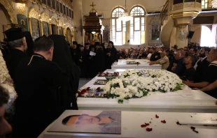 Mourners gather at the Church of the Holy Cross in Qassaa, Damascus, on June 24, 2025, around white caskets of some of the worshippers who lost their lives in a terrorist attack at the Mar Elias Church in the Dweila neighborhood of Syria’s capital on Sunday, June 22, 2025. Credit: Mohammad Al-Rifai/ACI MENA