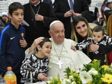 Pope Francis poses with a woman and three children during a lunch in the Vatican's Paul VI Hall for over 1,000 poor and economically disadvantaged people on Nov. 19, 2023.