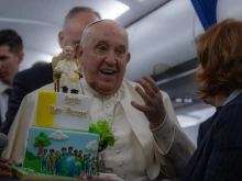 Pope Francis is presented with a birthday cake aboard the papal plane on the return from his trip to Corsica on Sunday, Dec. 15, 2024.