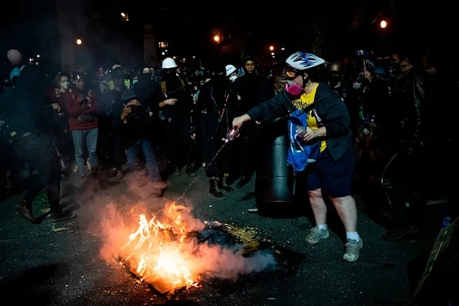 A demonstrator tries to put out a fire that other demonstrators started outside a U.S. courthouse during a protest on July 31, 2020 in Portland, Oregon. ?w=200&h=150