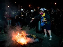 A demonstrator tries to put out a fire that other demonstrators started outside a U.S. courthouse during a protest on July 31, 2020 in Portland, Oregon. 