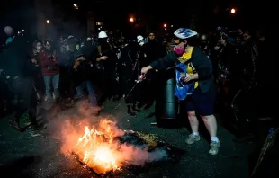 A demonstrator tries to put out a fire that other demonstrators started outside a U.S. courthouse during a protest on July 31, 2020 in Portland, Oregon.   Alisha JUCEVIC / AFP via Getty