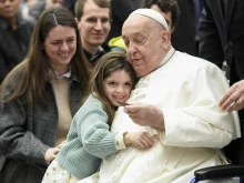 Pope Francis is hugged by a young visitor at his general audience at the Vatican, Wednesday, Feb. 12, 2025.