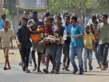 Sudanese carry a man injured during clashes as part of protests against a military coup that overthrew the transition to civilian rule, on Oct. 25, 2021 in the capital Khartoum. - Sudan's top general declared a state of emergency Monday as soldiers rounded up civilian leaders, with three people killed as soldiers put down furious protests decrying a coup.