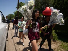 People arrive to drop off flowers at a makeshift memorial outside the Robb Elementary School on May 26, 2022 in Uvalde, Texas. - Grief at the massacre of 19 children at the elementary school in Texas spilled into confrontation on May 25, as angry questions mounted over gun control -- and whether this latest tragedy could have been prevented. The tight-knit Latino community of Uvalde on May 24 became the site of the worst school shooting in a decade, committed by a disturbed 18-year-old armed with a legally bought assault rifle.