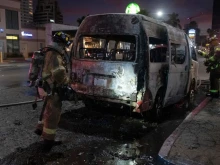 Firefighters work at the scene of a burnt collective transport vehicle after it was set on fire by unidentified individuals in Tijuana, Baja California state, Mexico, on Aug. 12, 2022.