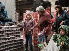 Lybicheva Nina, 72, along with her grandchildren receives food items during a distribution to about 3,000 people by the local branch of Caritas Internationalis, a Catholic charity organization, in Kharkiv, Ukraine, on Sept. 27, 2022.