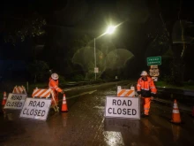 Road workers close the access to the 101 Freeway at Olive Mill Road as a result of San Ysidro Creek overflowing due to heavy rainfall in the area on Jan. 9, 2023, in Montecito, California. The town was ordered evacuated on Monday with firefighters warning mudslides could engulf homes. Montecito, a town of about 9,000 people, was expected to get up to eight inches of rain in 24 hours —on hillsides already sodden by weeks of downpours.