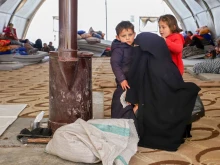 A Syrian woman and her children warm by a stove at an emergency shelter in the center of the city of Maarat Misrin, in the rebel-held northern part of the northwestern Idlib province Feb. 7, 2023, one day after a deadly earthquake hit Syria and Turkey.