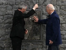 President Joe Biden and Father Richard Gibbons share an umbrella as President Biden touches the original stone from the apparition gable in the rain during a visit to Knock Shrine, on April 14, 2023, on the last day of a four-day trip to Northern Ireland and Ireland.