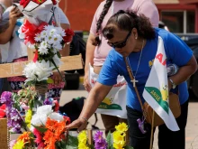 A woman touches crosses setup at a memorial during a vigil on May 8, 2023, in Brownsville, Texas. The vigil was held in remembrance of the eight people killed May 7, 2023, and several injured after a man allegedly drove his car through a group of migrants waiting at a bus stop.