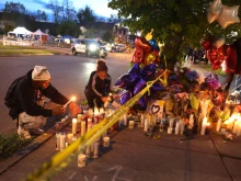 Mourners light candles at a makeshift memorial outside of Tops market on May 16, 2022 in Buffalo, New York. A gunman opened fire at the store yesterday killing ten people and wounding another three. The attack was believed to be motivated by racial hatred.