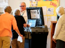 A poll worker helps a voter cast their ballot in the Kansas Primary Election at Merriam Christian Church on August 02, 2022 in Merriam, Kansas.