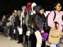 Immigrants seeking asylum in the United States stand in line to be processed by U.S. Border Patrol agents in the early morning hours after crossing into Arizona from Mexico on May 10, 2023, in Yuma, Arizona.