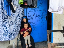 A woman sits with a child by drying laundry outside a classroom at a school run by the United Nations Relief and Works Agency for Palestine Refugees in the Near East (UNRWA) in Rafah in the southern Gaza Strip on Nov. 14, 2023, where internally displaced Palestinians have taken refuge amid ongoing battles between Israel and the Palestinian militant group Hamas.