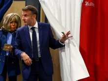 French President Emmanuel Macron and his wife, Brigitte Macron, exit a polling booth adorned with curtains displaying the colors of the flag of France before casting their ballot for the European Parliament election at a polling station in Le Touquet, northern France, on June 9, 2024.