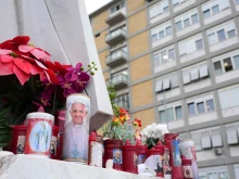 Candles are set at the feet of a statue of Pope John Paul II on Feb. 20, 2025, outside Gemelli Hospital in Rome, where Pope Francis is hospitalized for tests and treatment for bronchitis.