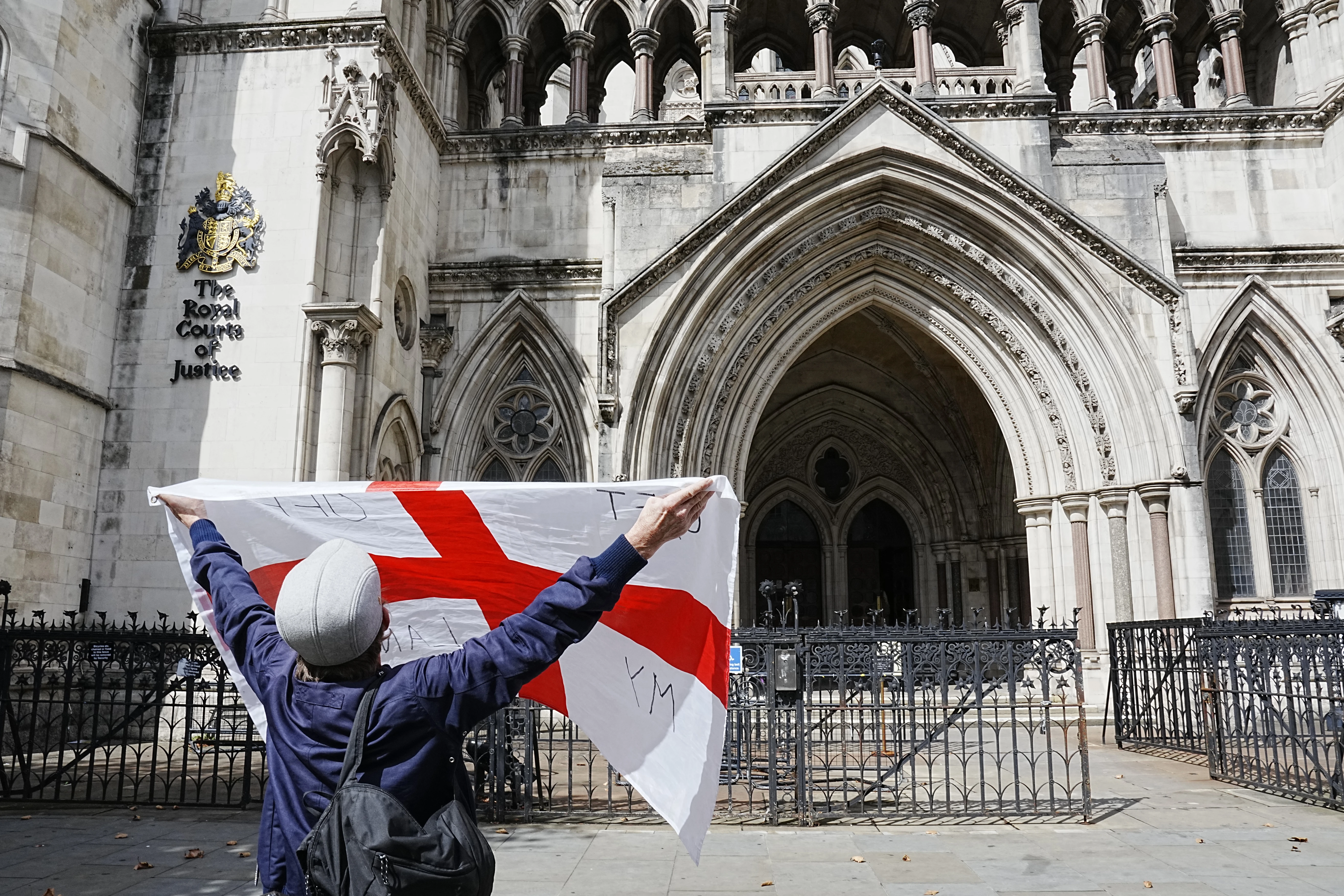 A protester holds up a St. George’s cross flag with the slogan “Get Off My Land” outside the High Court in London on Aug. 29, 2025, as the government seeks to challenge a High Court ruling that will stop asylum seekers from being housed at the Bell Hotel in Epping beyond Sept. 12.?w=200&h=150