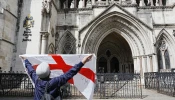 A protester holds up a St. George’s cross flag with the slogan “Get Off My Land” outside the High Court in London on Aug. 29, 2025, as the government seeks to challenge a High Court ruling that will stop asylum seekers from being housed at the Bell Hotel in Epping beyond Sept. 12.