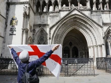 A protester holds up a St. George’s cross flag with the slogan “Get Off My Land” outside the High Court in London on Aug. 29, 2025, as the government seeks to challenge a High Court ruling that will stop asylum seekers from being housed at the Bell Hotel in Epping beyond Sept. 12.