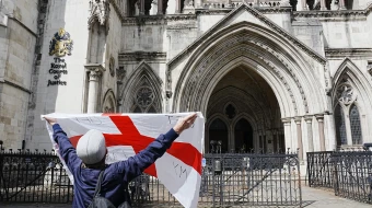 A protester holds up a St. George’s cross flag with the slogan “Get Off My Land” outside the High Court in London on Aug. 29, 2025, as the government seeks to challenge a High Court ruling that will stop asylum seekers from being housed at the Bell Hotel in Epping beyond Sept. 12.