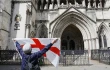 A protester holds up a St. George’s cross flag with the slogan “Get Off My Land” outside the High Court in London on Aug. 29, 2025, as the government seeks to challenge a High Court ruling that will stop asylum seekers from being housed at the Bell Hotel in Epping beyond Sept. 12.