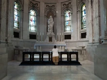A woman kneels to pray during a prayer service of peace and healing at the Cathedral of St. Paul held to address the shooting at Annunciation Catholic Church in neighboring Minneapolis on Aug. 28, 2025, in St. Paul, Minnesota. A gunman fired through the windows of Annunciation Church while students were sitting in pews during a Catholic school Mass, killing two children and injuring at least 17 others.