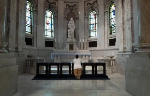 A woman kneels to pray during a prayer service of peace and healing at the Cathedral of St. Paul held to address the shooting at Annunciation Catholic Church in neighboring Minneapolis on Aug. 28, 2025, in St. Paul, Minnesota. A gunman fired through the windows of Annunciation Church while students were sitting in pews during a Catholic school Mass, killing two children and injuring at least 17 others. Credit: Scott Olson/Getty Images