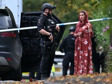 An armed police officer talks to a member of the local community outside Heaton Park Hebrew Congregation synagogue in Crumpsall, north Manchester, England, on Thursday, Oct. 2, 2025.