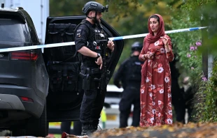 An armed police officer talks to a member of the local community outside Heaton Park Hebrew Congregation synagogue in Crumpsall, north Manchester, England, on Thursday, Oct. 2, 2025. Credit: OLI SCARFF/AFP via Getty Images