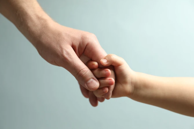 Adult holding child's hand