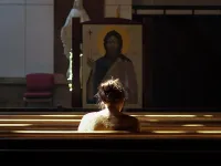 A woman sits alone in a Catholic church.