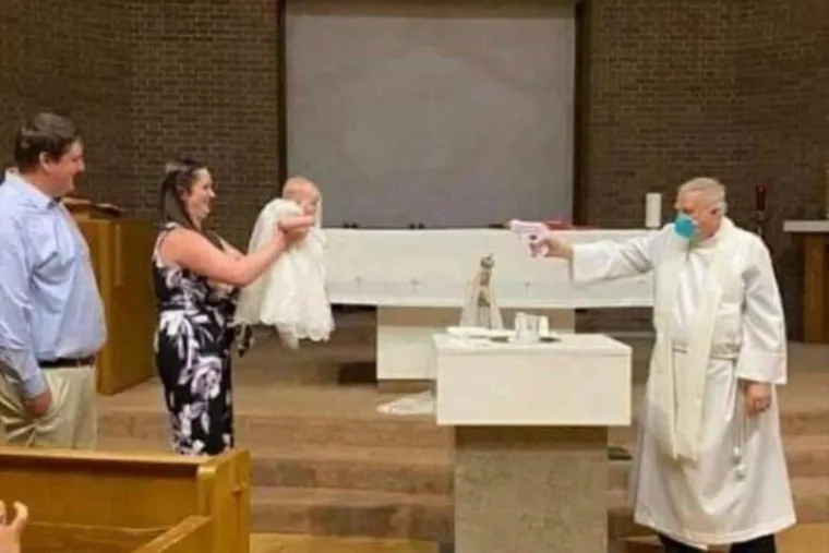 Fr. Stephen Klasek pretends to shoot water at a baby in this now-viral photo. Credit: Fair use.