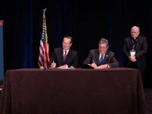Benedictine College President Stephen D. Minnis and Catholic Healthcare International founder and President Jere D. Palazzolo sign a Collaborative Affiliation Agreement Sept. 8, 2022 in Denver, Colorado, beginning the process of establishing an independent medical school on the Benedictine campus, as CHI board member Fr. Timothy Nelson, MD, looks on.