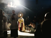 Attendees kneel and reach for the monstrance as it passes by them during a procession at the National Eucharistic Congress in Indianapolis, Indiana.