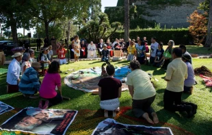 Participants kneel before bowing to a set of items during a tree planting ceremony in the Vatican gardens, Oct. 3, 2019.   Vatican Media.
