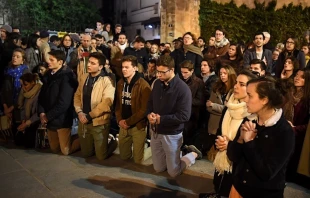 People kneel on the pavement as they pray outside watching flames engulf Notre-Dame Cathedral in Paris, April 15, 2019.   Eric Feferberg/AFP/Getty Images.