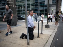 A man kneels as the National Eucharistic Procession passes by in Philadelphia on May 30, 2024.