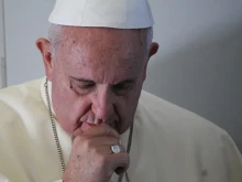 Pope Francis prays with journalists on a papal flight August 14, 2014.