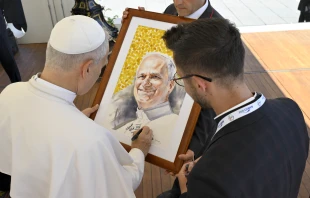 Pope Leo XIV signs a portrait of himself for a pilgrim at his general audience on July 30, 2025, in St. Peter’s Square at the Vatican. Credit: Vatican Media