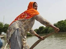 A woman rows a boat in Sindh, Pakistan, where swollen rivers swept away homes and destroyed crops and bridges. Photo by Laura Sheahen/CRS