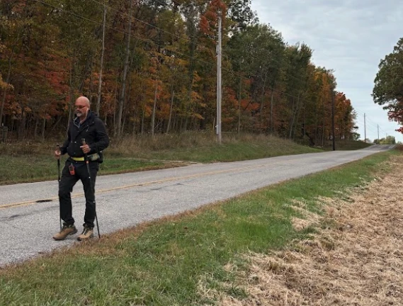 Father Gary Graf walks down a rural road during his trek across America in support of immigrants on Friday, Oct. 17, 2025.?w=200&h=150