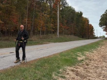 Father Gary Graf walks down a rural road during his trek across America in support of immigrants on Friday, Oct. 17, 2025.