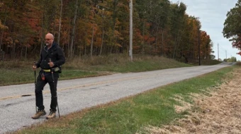 Father Gary Graf walks down a rural road during his trek across America in support of immigrants on Friday, Oct. 17, 2025.