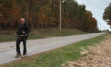 Father Gary Graf walks down a rural road during his trek across America in support of immigrants on Friday, Oct. 17, 2025.